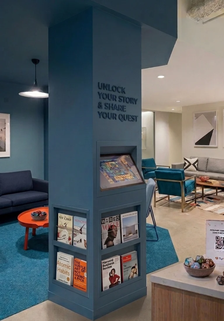 Touchscreen puzzle station built into a lounge pillar with books and magazines